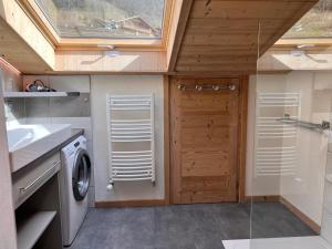 a bathroom with a washing machine and a wooden door at Gentianes 4 - Appartement centre village in La Clusaz