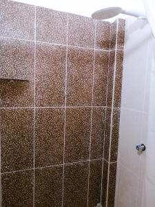 cabina de ducha con azulejos marrones y blancos en Habitación en la playa en Tumbes