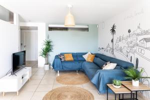 un salon avec un canapé bleu et une télévision dans l'établissement plage st jean RESIDENCE LE GOLFE D AZUR, à La Ciotat