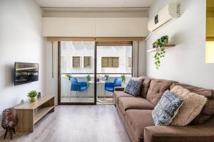 uma sala de estar com um sofá castanho e cadeiras azuis em Eleni’s 1-BR Apt in Larnaca Center em Lárnaca