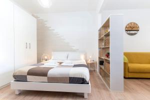 a white bedroom with a bed and a yellow chair at Casa Sasà in Ostuni