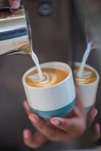 a person is pouring milk into a cup of coffee at Ecozy Dijiwa Canggu in Canggu