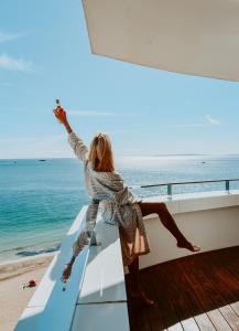 a woman is sitting on a balcony overlooking the ocean at Ushuaia Ibiza Beach Hotel - Adults Only in Playa d'en Bossa