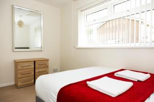 a bedroom with a bed with a red blanket and a mirror at Alexander Apartments Durham in Chester-le-Street