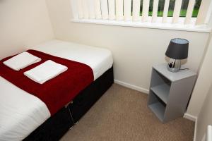 a small bedroom with a bed with a red blanket at Alexander Apartments Durham in Chester-le-Street