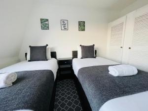 two twin beds in a room with white walls at Cheerful 5-bedroom with free parking in Bristol