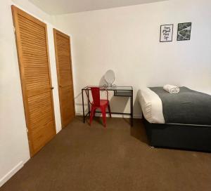 a bedroom with a bed and a desk with a red chair at Cheerful 5-bedroom with free parking in Bristol