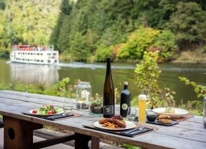 a wooden table with plates of food and a bottle of wine at Saarschleifenlodge in Dreisbach