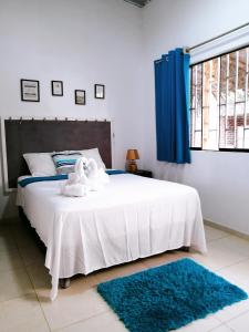 a bedroom with a large white bed with blue curtains at Vista Palmeras in Zorritos