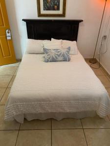Una cama blanca con dos almohadas encima. en Great Savannah Guesthouse en Sabana Grande