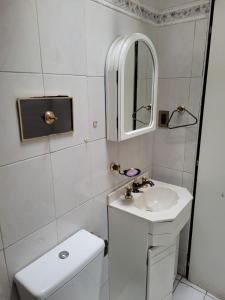 a white bathroom with a sink and a mirror at Casa Balcarce in Godoy Cruz