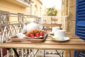 un tavolo con vassoio di fragole e tazze sul balcone di Gawhra B&B a Victoria