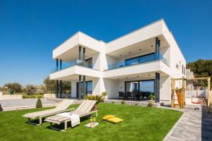 a white house with a lawn and two chairs at Luxury Apartment Blue Sky in Pakoštane