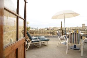 un patio con sedie, un tavolo e un ombrellone di Gawhra B&B a Victoria