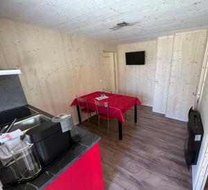 a room with a table with a red table cloth at Bungalow Miralago in Camping Cavresc, Via dal Cavresc 1, 7746 Le Prese-Poschiavo in Poschiavo