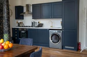 a kitchen with navy blue cabinets and a washing machine at Charrington House in London