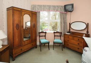 a bedroom with a dresser and two chairs and a mirror at Gleneven Guest House in Inniskeen