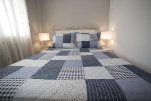 a bedroom with a bed with a blue and white quilt at Apartamentos Eldorado in Lloret de Mar
