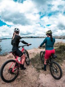 dos mujeres montando bicicletas junto a un cuerpo de agua en Costa Azul Ecolodge, en Aquitania