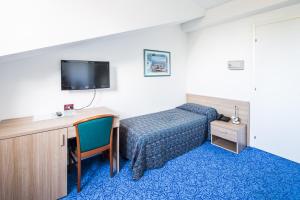 um quarto de hotel com uma cama, uma secretária e uma televisão em Hotel Olympia em Lignano Sabbiadoro