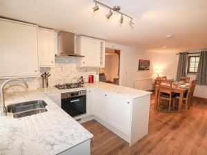 a kitchen with white cabinets and a counter top at Fryston Cottage in Keswick