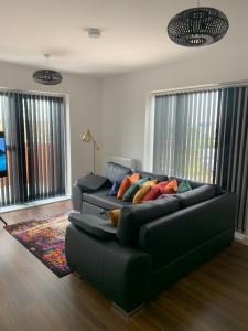 ein Wohnzimmer mit einem schwarzen Sofa und bunten Kissen in der Unterkunft Lakeside 2 BED LUXURY APARTMENT No PARTIES No EVENTS Early Check-in Late Check- Out Allowed in West Thurrock