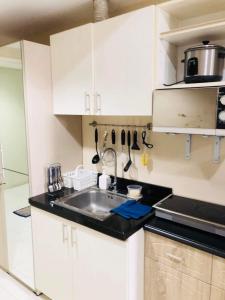 Una cocina con gabinetes blancos y un fregadero. en Bay View Apartment Sunvida Tower 28, en Cebú