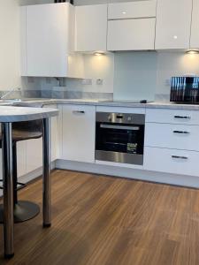 a kitchen with white cabinets and a black oven at Lakeside 2 BED LUXURY APARTMENT No PARTIES No EVENTS Early Check-in Late Check- Out Allowed in West Thurrock