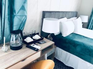 a bedroom with a bed and a table with a lamp at Gabz Airport Inn in Gaborone