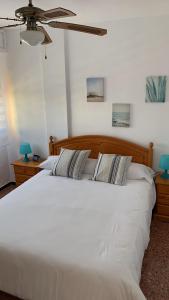 uma grande cama branca num quarto com uma ventoinha de tecto em Apartamento La Pobla de Farnals em Valência