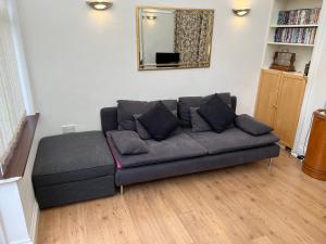 un sofá en la sala de estar con espejo en Edencourt Apartment en Londres
