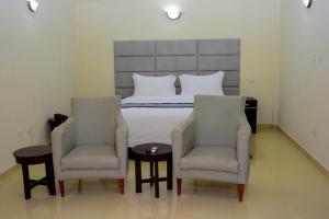 a bedroom with a bed with two chairs and a bed at TD RESIDENCE INN in Ijebu Ode