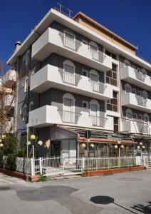 a large white building with balconies on a street at Hotel Sabbia d'Oro in Rimini
