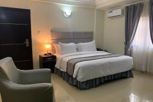 a bedroom with a large bed and a chair at TD RESIDENCE INN in Ijebu Ode