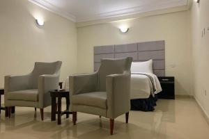 a bedroom with two chairs and a bed in it at TD RESIDENCE INN in Ijebu Ode