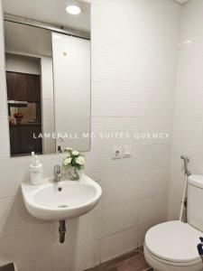 een badkamer met een wastafel, een toilet en een spiegel bij Lamerall MG Suites Quency in Semarang