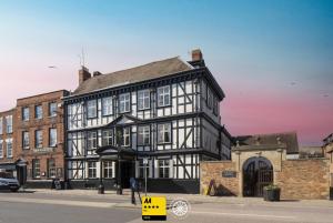 a black and white building on the corner of a street at The Tudor House Hotel, Tewkesbury, Gloucestershire in Tewkesbury