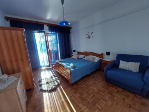 a bedroom with a blue bed and a blue couch at Apartman Aurora in Čara