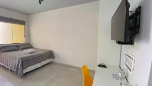 1 dormitorio con 1 cama y TV de pantalla plana en Kalug - Apt Studio em Guest House na Praia do Sul, en Ilhéus