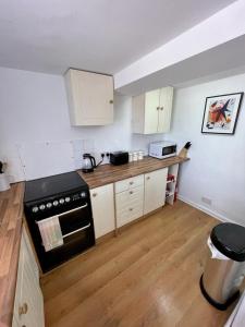 a kitchen with white cabinets and a black stove at Number 8 Clandown in Radstock