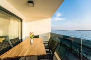 a wooden table and chairs on a balcony with the ocean at Blue waves, beachfront modern apartment in Mandre
