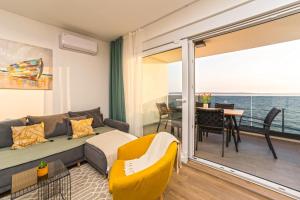 a living room with a couch and a balcony at Blue waves, beachfront modern apartment in Mandre