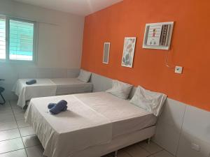 Habitación con 2 camas y pared de color naranja. en Casa Recife Pousada en Recife