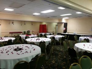 een vergaderzaal met tafels en stoelen met rode bloemen erop bij Jackson Hotel & Convention Center in Jackson