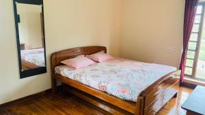 1 dormitorio con cama de madera y espejo en Kee2 Wood House en Kodaikānāl