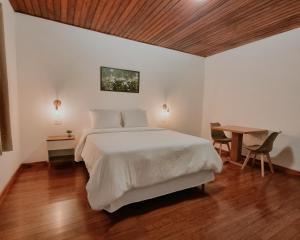 Un dormitorio con una gran cama blanca y una mesa en Casa Wald en Campos do Jordão