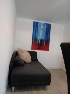 BirkenbeulにあるSchönes Appartement " Die Ponybude" auf unserem Reiterhofの壁画のある部屋の黒いソファ