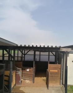 a barn with a roof and boxes on the ground at Schönes Appartement " Die Ponybude" auf unserem Reiterhof in Birkenbeul