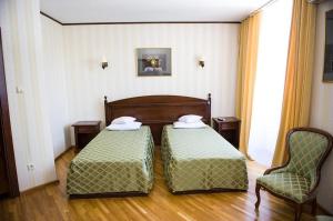 twee bedden in een kamer met twee stoelen bij Pensiunea Eden Caransebes in Caransebeş