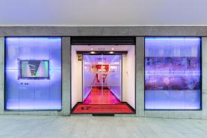 Art Seven Hostel Capsules في مدريد: واجهة متجر مع نوافذ أرجوانية واضاءة زرقاء